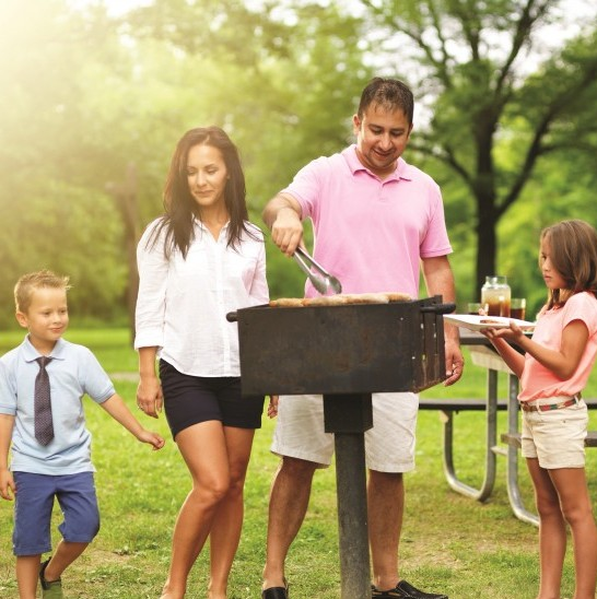 Practice the following Labor Day safety tips for an enjoyable weekend. This image features a family grilling at a park.
