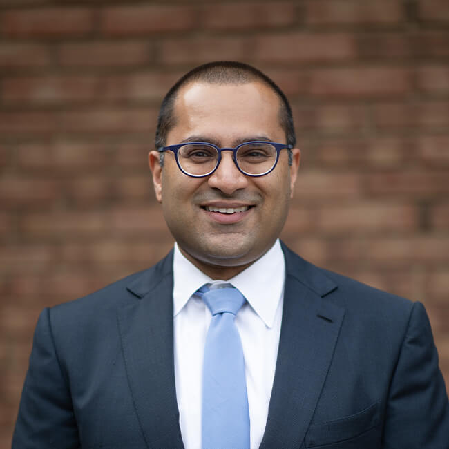 Dr. Avery Arora smiles in a headshot taken outside of his office.