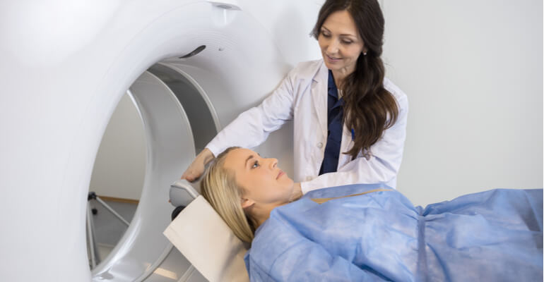 A woman is guided into a CT scan.
