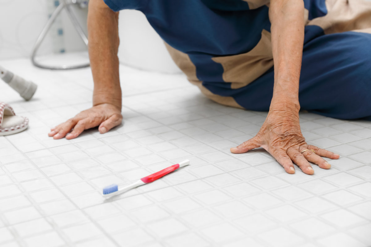 Bathroom injury prevention tips include placing slip-resistant decals on the bathroom floor, as well as placing grab bars around the toilet and bathtub. This image shows a senior holding herself up on her hands after a fall on a bathroom floor.